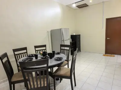 a dining room with a table and chairs and a refrigerator at Padang Serai Premier Home in Kampong Dekeh