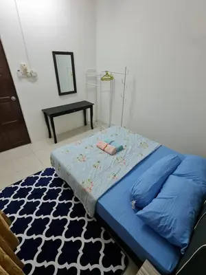 a bed with a blue comforter in a room at Azam Homestay in Seri Manjung
