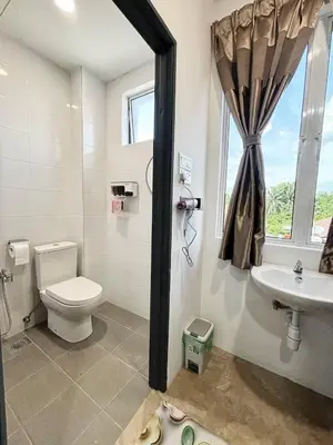a bathroom with a toilet and a sink and a window at Trace Cozy Place in Teluk Intan