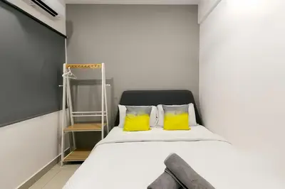 a bedroom with a bed with two yellow pillows at Manhattan Suites Ipoh in Kampong Makam