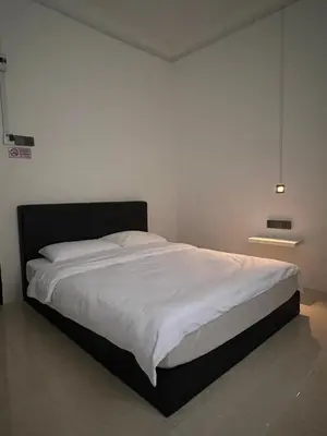 a bedroom with a large bed with white sheets at 23 Inn Queenbed Room with share bathroom in Simpang Ampat
