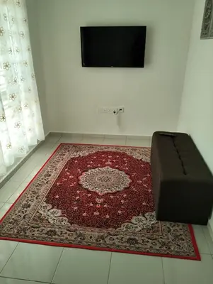 a room with a rug and a couch and a tv at Arima Homestay A in Permatang Janggus