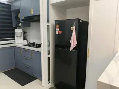 a black refrigerator in a kitchen with blue cabinets at Homestay Coway Bertam in Kampong Sungai Korok