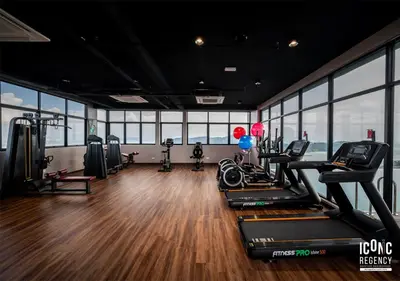 a gym with treadmills and ellipticals in a room with windows at Iconic Regency Service Residences, managed by Iconic Hotel in Bayan Lepas