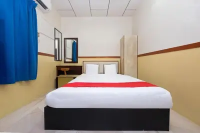 a bedroom with a large white bed with blue curtains at Lumut Villa Inn in Kampong Tebing Rabak
