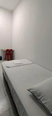 a large white bed in a room with a red chair at Homestay Bandar Puteri Jaya in Sungai Petani