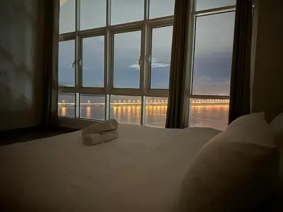 a white bed with a towel sitting on it in front of a window at Seaview Vacation Condo 3R3B 8Pax in Kampong Batu Maung
