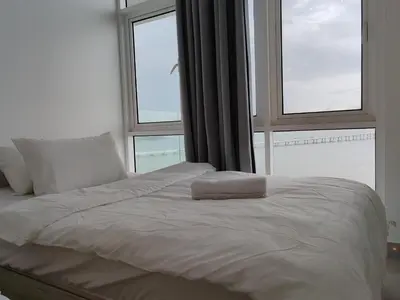 a bed with a pillow on it in front of a window at Seaview Vacation Condo 3R3B 8Pax in Kampong Batu Maung