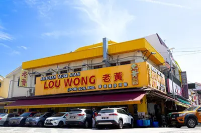 a yellow building with cars parked in front of it at De Quinton Hotel in Ipoh