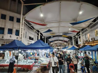 a group of people walking around a market with blue tents at De Quinton Hotel in Ipoh