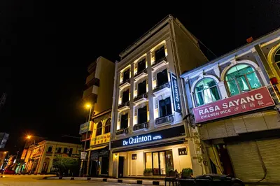 a building with a sign on the side of it at night at De Quinton Hotel in Ipoh