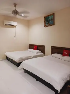 two beds in a room with red pillows on them at Hotel Kavanass Inn in Simpang