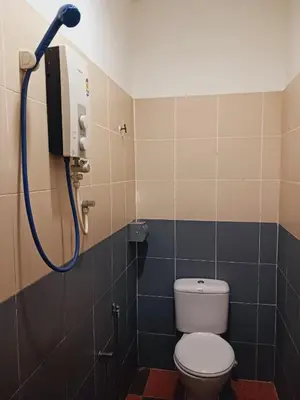 a bathroom with a toilet and a shower at Hotel Kavanass Inn in Simpang