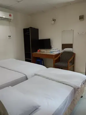 a room with two beds and a desk with a computer at Hotel Kavanass Inn in Simpang