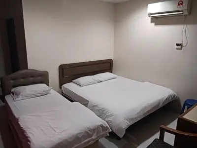 two beds in a room with white sheets at Hotel Kavanass Inn in Simpang