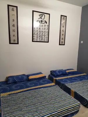 three beds in a room with signs on the wall at \u4f18\u96c5\u805a\u6c11\u5bbf in Kampong Kuala Punti