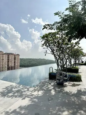 a swimming pool with a tree next to a body of water at Urban Seaview with Infinity Pool, Luxury Modern Stylish 7pax 3Bedroom 3Queen in Jelutong