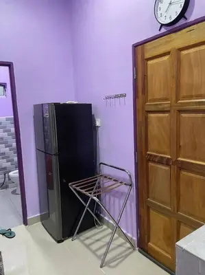 a black refrigerator next to a wall with a clock at Sekinchan Homestay Teratak AZ - muslm only in Kampong Batu Dua Puloh Tiga