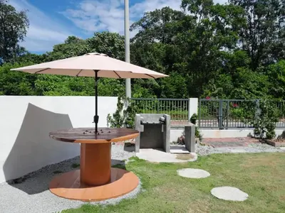 a wooden table with an umbrella in the grass at SimpleHome in Tupai
