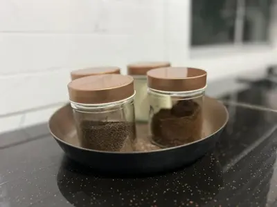 three jars of seasoning sitting in a bowl on a counter at D'Nuha homestay Unit 2 Chenderong Balai Teluk Intan in Kampung Degong
