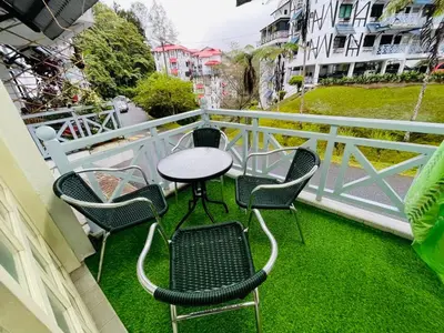 a table and chairs on a balcony with green grass at INAP DESA ANTHURIUM CAMERON HiGHLANDS in Tanah Rata