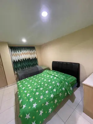 a bedroom with a green bedspread with stars on it at INAP DESA ANTHURIUM CAMERON HiGHLANDS in Tanah Rata
