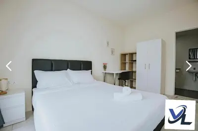 a bedroom with a large white bed and a table at Close Dun Book in Ipoh