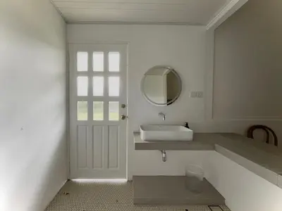 a white bathroom with a sink and a mirror at The Petrichor in Tupai
