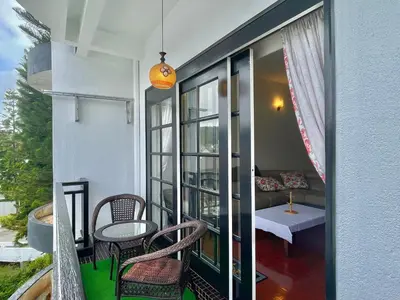 a balcony with chairs and a table and a couch at Cozy Cottage-Style Apartment Entire Unit in Tanah Rata