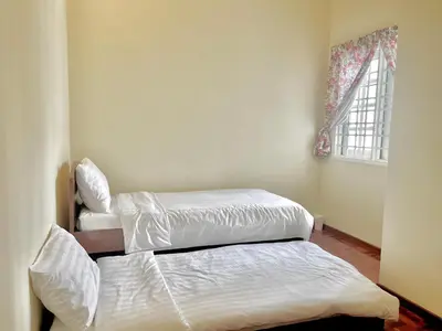 two twin beds in a room with a window at Cozy Cottage-Style Apartment Entire Unit in Tanah Rata