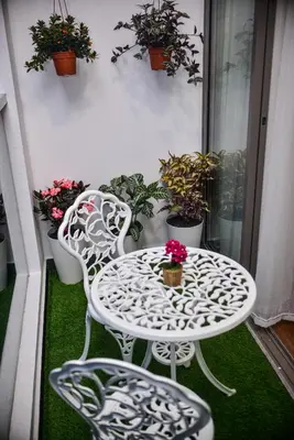 a white table and chairs on a balcony with potted plants at Cameron Palas Homestay - Sunrise View in Brinchang