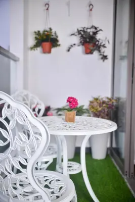 a white table and chairs on a balcony with potted plants at Cameron Palas Homestay - Sunrise View in Brinchang