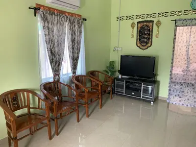 a living room with chairs and a flat screen tv at Teratak Annur Homestay in Tanjung Karang