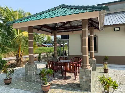 a patio with a table and chairs under a pergola at Teratak Annur Homestay in Tanjung Karang