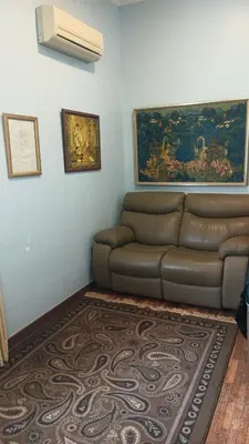 a living room with a brown couch and a painting at Will Ma in Ayer Itam