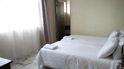 a bedroom with two beds with white sheets and a window at Bercham Vacation House in Ipoh