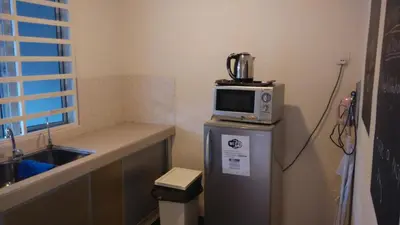 a small kitchen with a microwave on top of a refrigerator at Bercham Vacation House in Ipoh