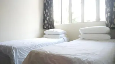 two beds in a room with white sheets and pillows at Bercham Vacation House in Ipoh