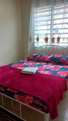 a bed with a red and blue blanket and a window at CozyStayz Perak in Sitiawan