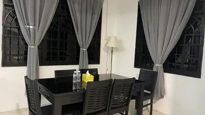 a black dining room table with chairs and curtains at Homestay Rumah 25 in Sungai Petani