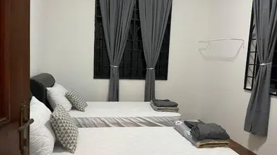 a room with two beds and a window with curtains at Homestay Rumah 25 in Sungai Petani
