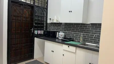 a kitchen with a sink and a black tile wall at Homestay Rumah 25 in Sungai Petani