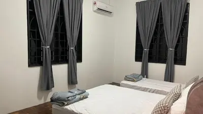 two beds in a room with black curtains at Homestay Rumah 25 in Sungai Petani