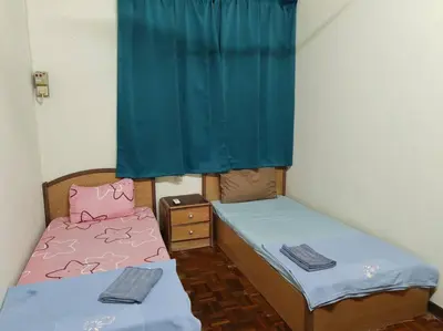 two beds in a small room with blue curtains at Bayu Emas Batu Ferringhi 2 in Ayer Itam
