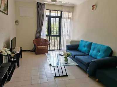 a living room with a blue couch and a glass table at Bayu Emas Batu Ferringhi 2 in Ayer Itam