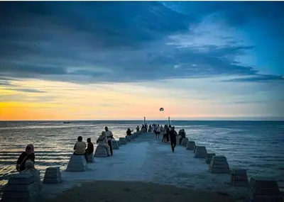 a group of people walking on the beach at sunset at Sri sayang pearl view in Batu Ferringhi