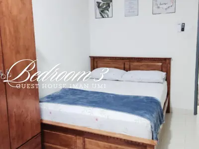 a bedroom with a bed with a wooden headboard at Guest House Iman Umi Bagan Serai in Bagan Serai