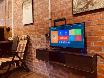 a television sitting on a stand next to a brick wall at Homestay Damai D'Sawah in Kampong Parit Fourteen