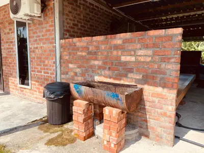 a brick wall with a bench next to a trash can at Homestay Damai D'Sawah in Kampong Parit Fourteen