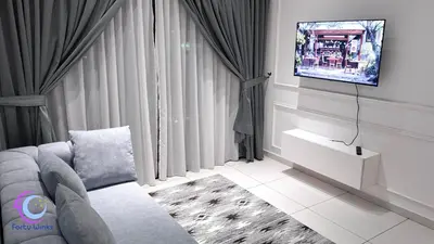 a living room with a couch and a tv on a wall at The Horizon Ipoh by 40 Winks in Ipoh